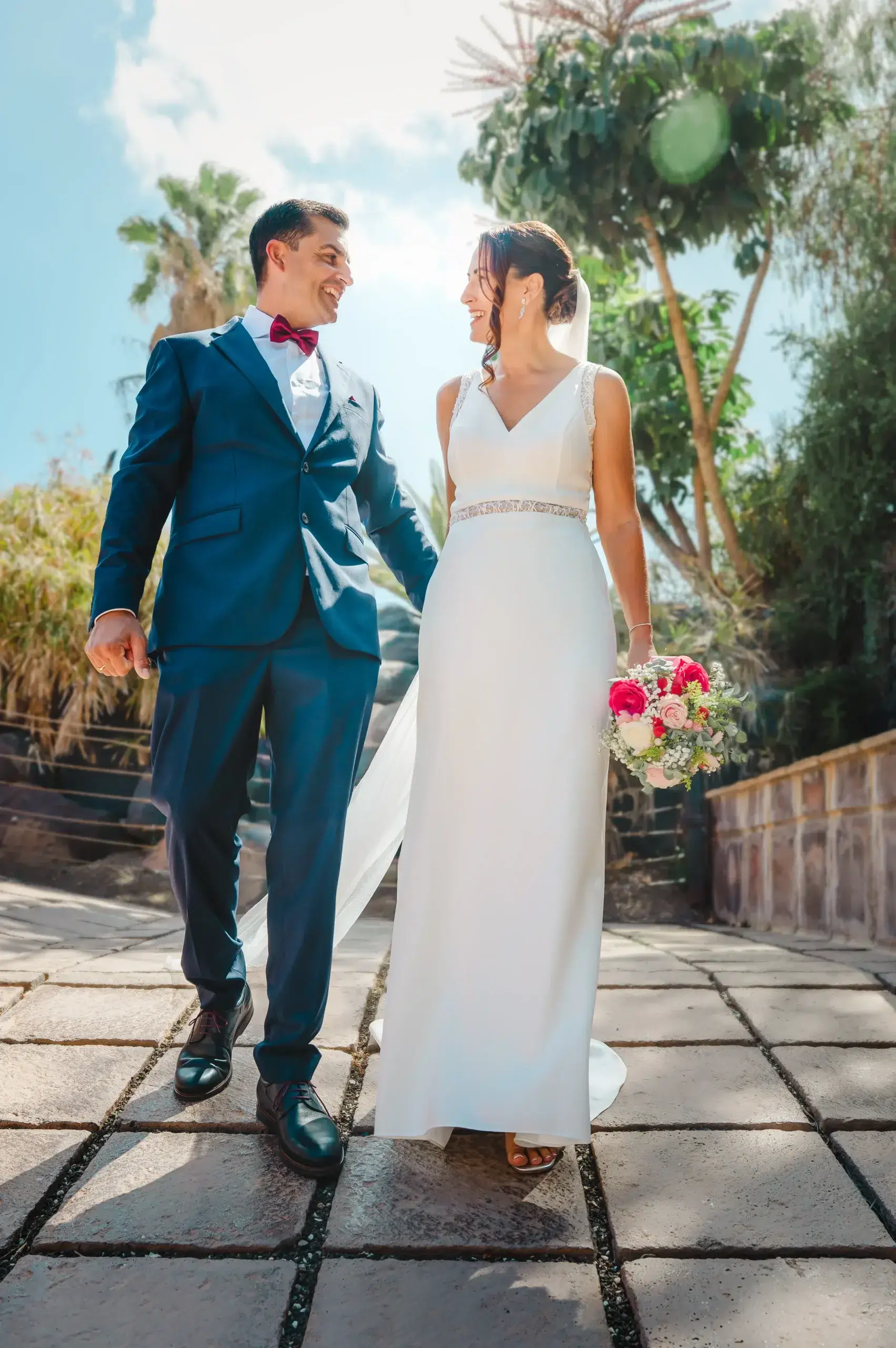 Una pareja de novios camina de la mano y se mira durante su boda en Las Palmas.
