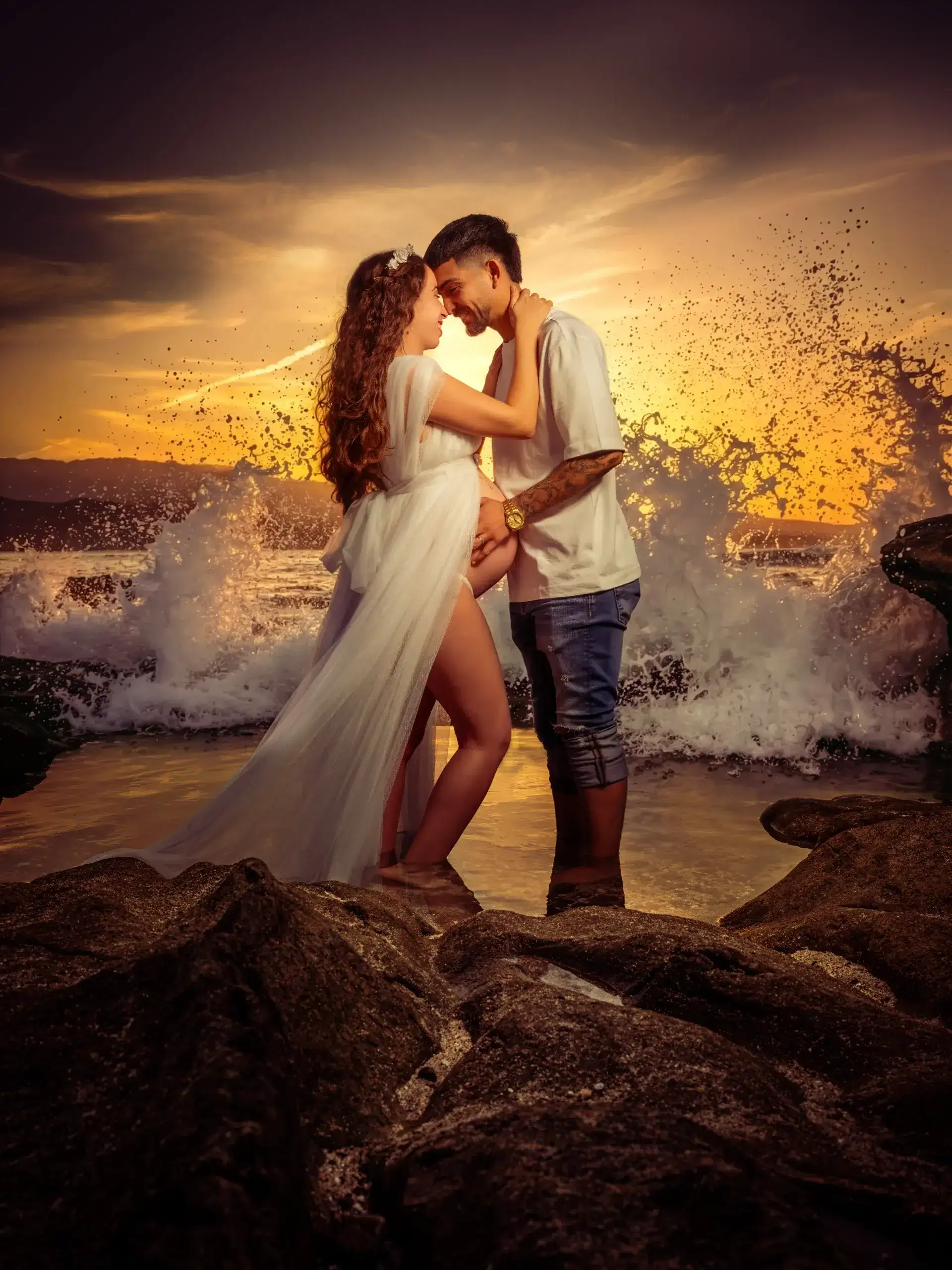 Una pareja se abraza durante el embarazo, frente a las olas y la luz del atardecer en Gran Canaria.